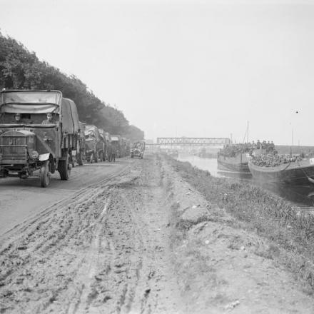 Truppe britanniche su chiatte sul canale Furnes-Dunkerque e una fila di camion lungo la strada a fianco. © IWM (Q 3875)