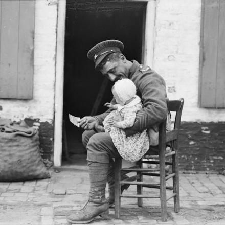 Soldato britannico che si occupa di un bambino fuori dal suo alloggio ad Adinkerke, vicino a Dunkerque, il 6 agosto 1917. © IWM (Q 2687)