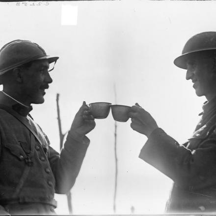 Un soldato francese e un sergente della Royal Garrison Artillery brindano insieme con una razione di vino francese a Boezinge, il 18 agosto 1917. © IWM (Q 2742)