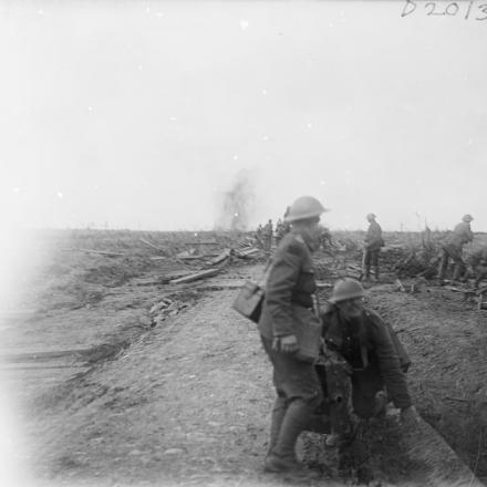 Una granata scoppia su una strada vicino a Ypres.  In primo piano due cameramen con le loro attrezzature. © IWM (Q 5949)