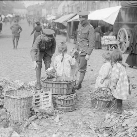 Soldati britannici che comprano cibo dai bambini nella piazza del mercato a Cassel, il 12 settembre 1917. © IWM (Q 2880)