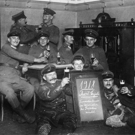 Truppe tedesche che brindano al felice anno nuovo del 1918 nel loro alloggio. Il messaggio sui tabelloni recita: "Kameraden trinkt im Osten schon für Frieden winkt - I compagni dell'Est bevono già per la pace". © IWM Q 88021