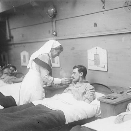 Un'infermiera si occupa di un soldato in un reparto dell'ospedale predisposto su una chiatta vicino ad Aire, il 15 febbraio 1918. © IWM Q 10667