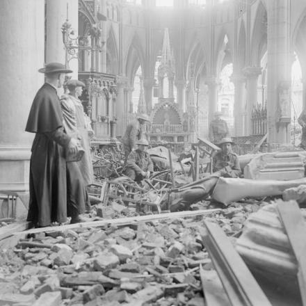 Soldati britannici che aiutano padre Leon Peulmeule, il curato temporaneo di Armentieres, a rimuovere quadri e statue dalla chiesa di Saint Vaast danneggiata dal fuoco delle granate. Armentieres, 26 febbraio 1918. © IWM Q 8545