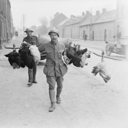 Un soldato francese, seguito da un soldato britannico, che trasporta polli alla sua mensa. Amiens, 28 marzo 1918. © IWM (Q 11575)