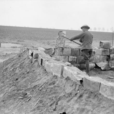 Soldato britannico che riempie le latte dei biscotti con la sabbia per usarle come materiale da costruzione. Vicino ad Arras, aprile 1918. © IWM (Q 8661)