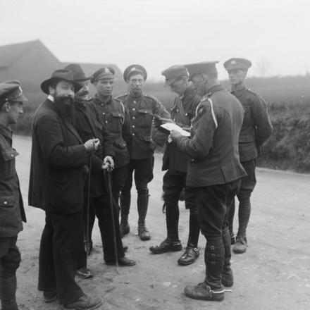 Truppe della Sezione Trasporti del 9 ° Battaglione, il Reggimento di Manchester esaminano i documenti di due civili, il 9 aprile 1918. © IWM (Q 11585)