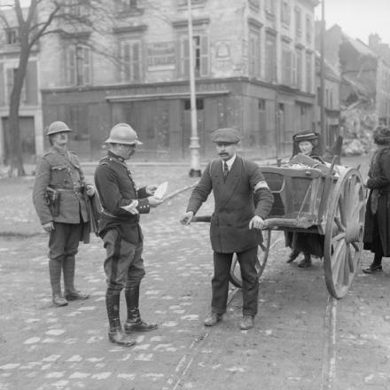 Poliziotto militare francese, accompagnato da quello britannico, che esamina i passaporti dei rifugiati civili che transitano per Amiens, il 29 aprile 1918. © IWM (Q 23607)