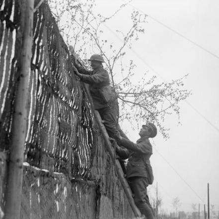 Soldati britannici erigono uno schermo mimetico accanto a una strada ad Abeele, vicino a Poperinghe, il 6 maggio 1918. © IWM (Q 8803)