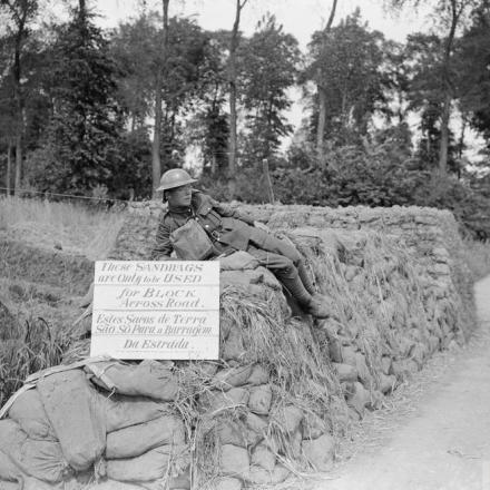 Sacchi di sabbia accatastati sul ciglio della strada. Robecq, 18 giugno 1918. Tabellone in inglese e in portoghese: "Questi sacchi devono essere utilizzati solo per realizzare un blocco stradale". © IWM (Q 7910)