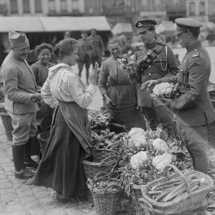 Artigliere della Royal Field Artillery che contratta con una contadina francese che vende verdura nel mercato di Saint-Omer, il 13 luglio 1918. © IWM (Q 11073) 