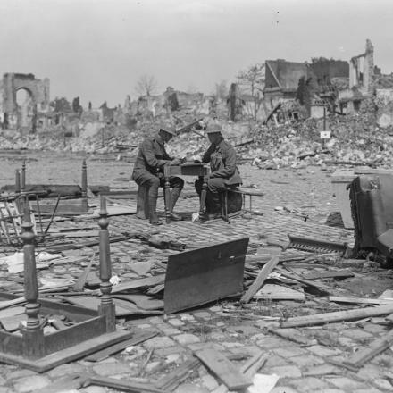 Soldati britannici seduti sui mobili nelle rovine di Bethune, con i resti della chiesa di St. Vaast sullo sfondo, il 16 luglio 1918.