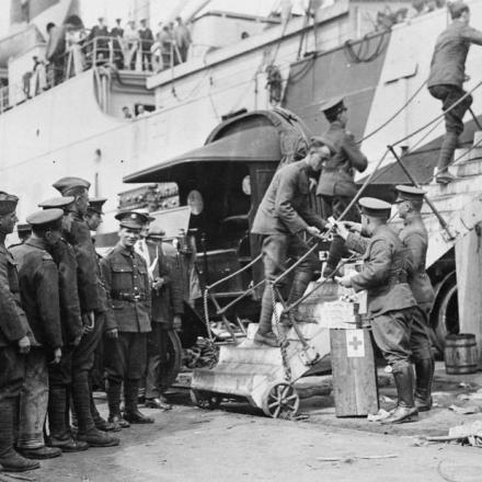 Ufficiali americani che distribuiscono sigarette a soldati americani e inglesi mentre salgono a bordo dell'HMS diretto verso la Russia al Royal Albert Docks, Londra, il 25 agosto 1918. © IWM (Q 85387)