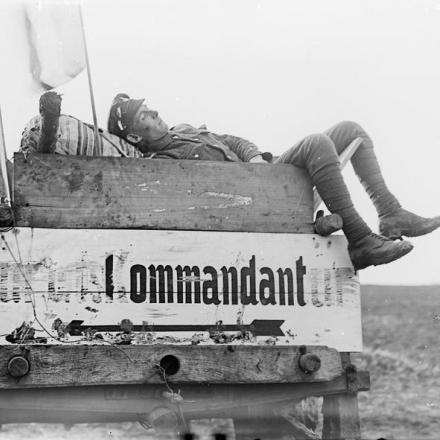Un soldato britannico addormentato su una bacheca tedesca "zur Ortskommandantur", Ath, novembre 1918. © IWM (Q 3367)