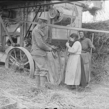 Soldato dell'Army Service Corps dell'esercito che aiuta i lavoratori agricoli francesi con una trebbiatrice Ruston, Corbie. © IWM (Q 3947)
