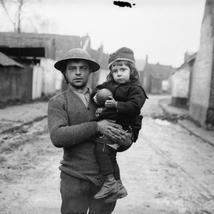 A Gouzeaucourt un soldato britannico tiene in braccio una bambina salvata a Masnieres, il 22 novembre 1917. © IWM (Q 3204)