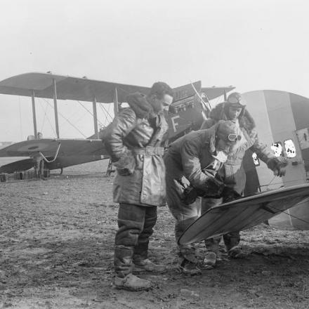Piloti che studiano le mappe sull'elevatore di un bombardiere diurno De Havilland. Aeroporto di Serny, 17 febbraio 1918. © IWM Q 12021