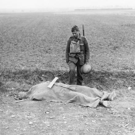 Il corpo di un soldato britannico sul ciglio della strada in attesa di sepoltura. La croce di legno è già pronta. Vicino a Domart, il 3 aprile 1918. © IWM (Q 11579)