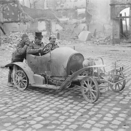 Tre soldati britannici si divertono a Cambrai con i resti di un'automobile, l'11 ottobre 1918. © IWM (Q 11803)