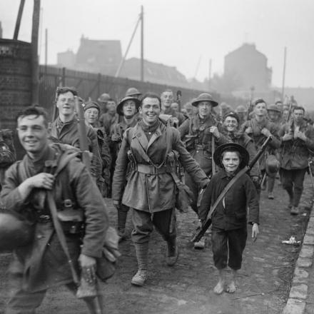 Truppe dell'8 ° battaglione, i King's (Liverpool Regiment, Liverpool Irish, 57th Division) entrano a Lille, il 18 ottobre 1918. Un ragazzo francese scalzo con un fucile, chiaramente dato a lui da un soldato sorridente alla sua destra. © IWM (Q 9574)