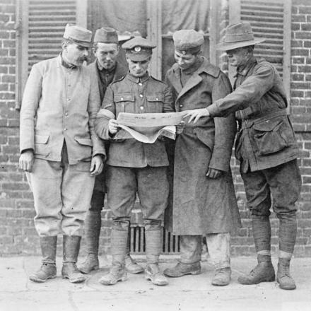 Soldato britannico, francese, americano e australiano con un prigioniero tedesco che legge il messaggio del presidente Wilson al Kaiser.  Corbie, il 24 ottobre 1918. © IWM (Q 49809)