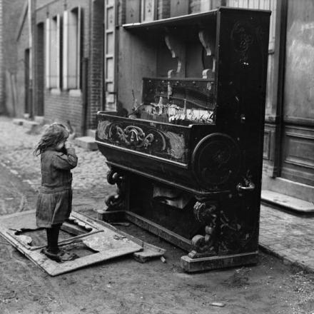 Una bambina guarda un pianoforte rotto in una strada di Denain, il 25 ottobre 1918. © IWM (Q 3308)