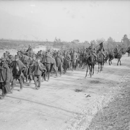 Lancieri italiani che scortano prigionieri austro-ungarici lungo la riva del fiume Meduna attraversato dalle truppe alleate, novembre 1918. © IWM (Q 26730)