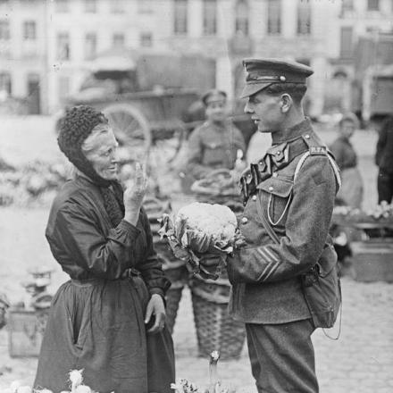 Artigliere della Royal Field Artillery che contratta con una contadina francese che vende verdura nel mercato di Saint-Omer, il 13 luglio 1918. © IWM (Q 11073) 