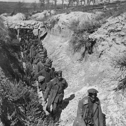 Lunga fila di prigionieri tedeschi che scendono da una trincea di comunicazione francese guidati da due dei loro ufficiali, il 25 settembre 1918. Regione di Tahure, Marne. © IWM (Q 70062)